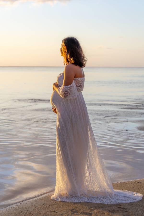 Future maman en robe blanche au bord de l'eau