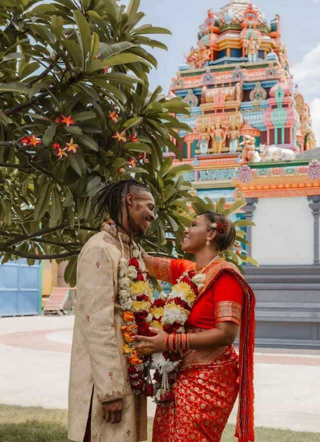 Mariés en tenue traditionnelle devant un temple tamoul